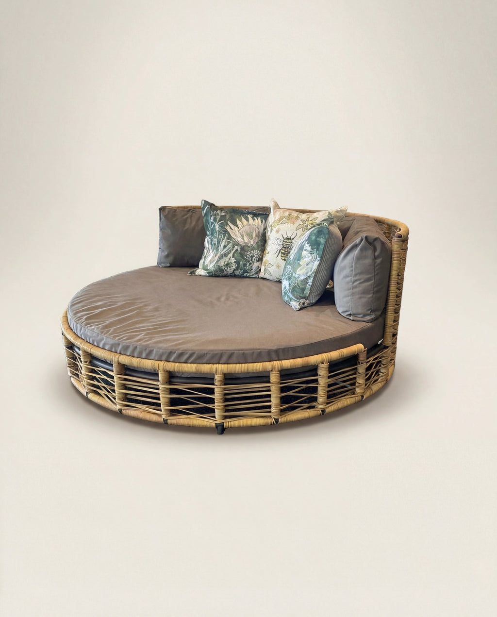 Round rattan daybed with cushions on a plain background