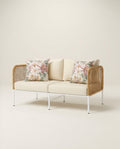 Two-seater outdoor sofa with floral cushions on a light background