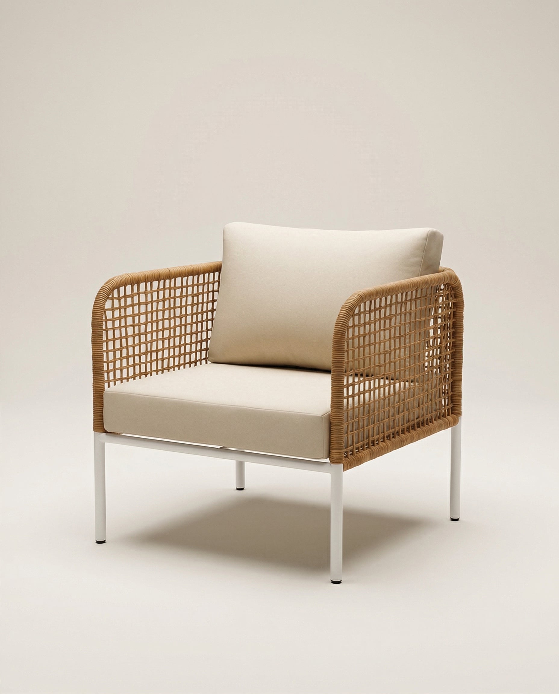 Wicker armchair with beige cushion on a light background
