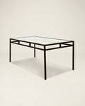 Glass table with black metal frame on a beige background